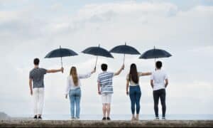 Menschen halten sich gegenseitig den Schirm.