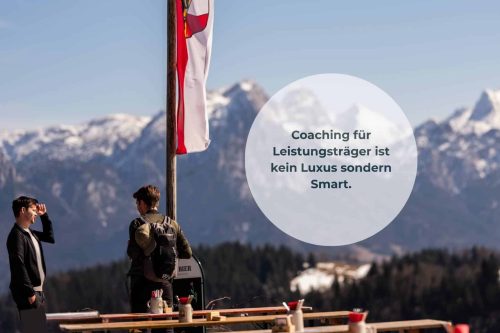 2 junge Männer auf einer Almhütte am reden vor dem Bergpanorama