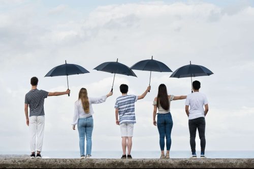 Menschen halten sich gegenseitig den Schirm.
